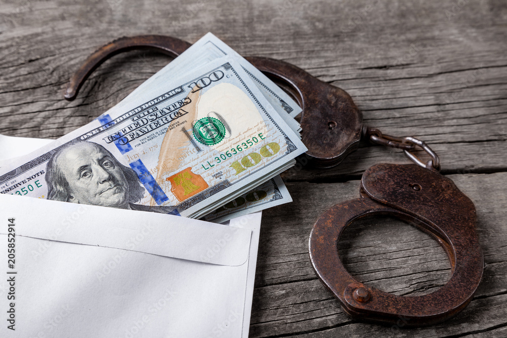Bribe, an envelope with money and handcuffs on wooden table. Theft of official money from the country's budget, concept Bribe, an envelope with money and handcuffs on wooden table. Theft of official money from the country's budget, concept