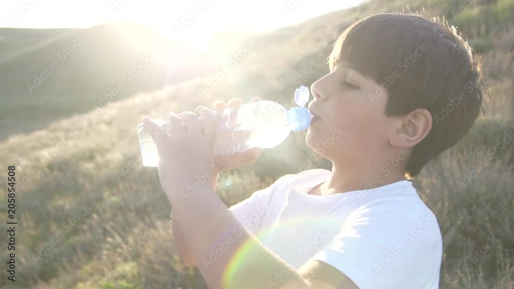 Boy is drinking water from plastic bottle Sun rays is shine Boy is drinking water from plastic bottle Sun rays is shine
