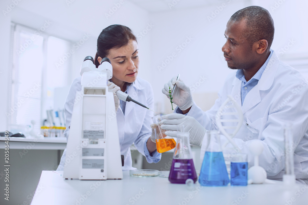 Best team. Experienced skilled researcher conducting a test and her colleague helping her Best team. Experienced skilled researcher conducting a test and her colleague helping her