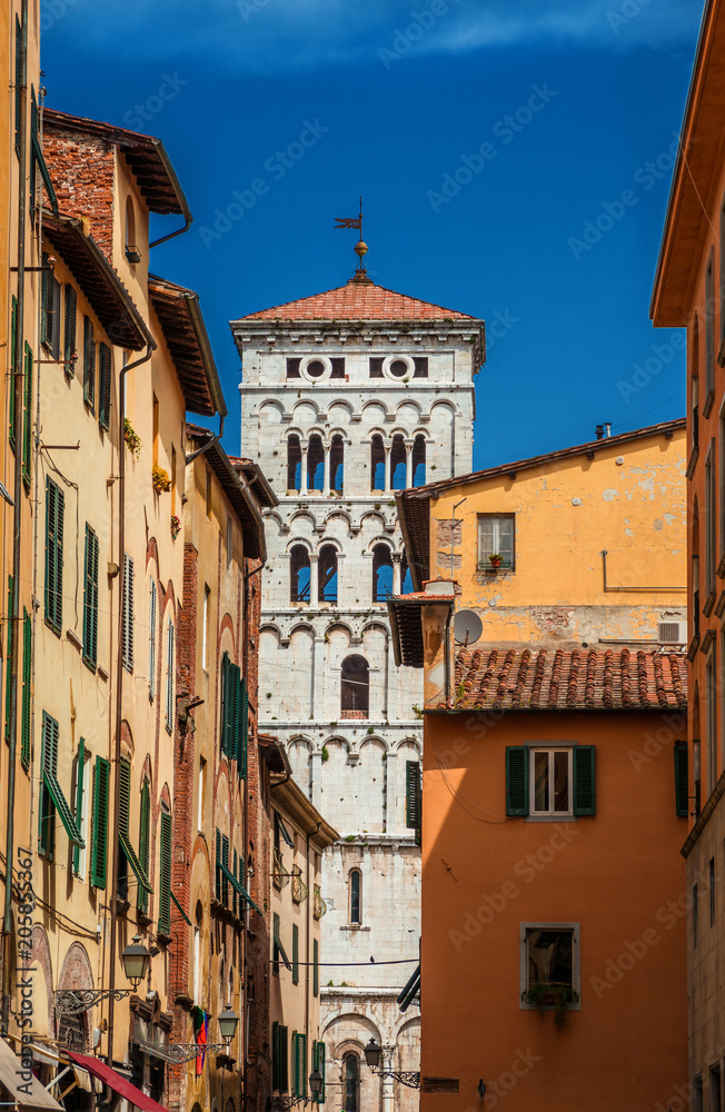 View of Lucca historic center with Saint Michael in Foro medieval bell tower seen from city narrow street