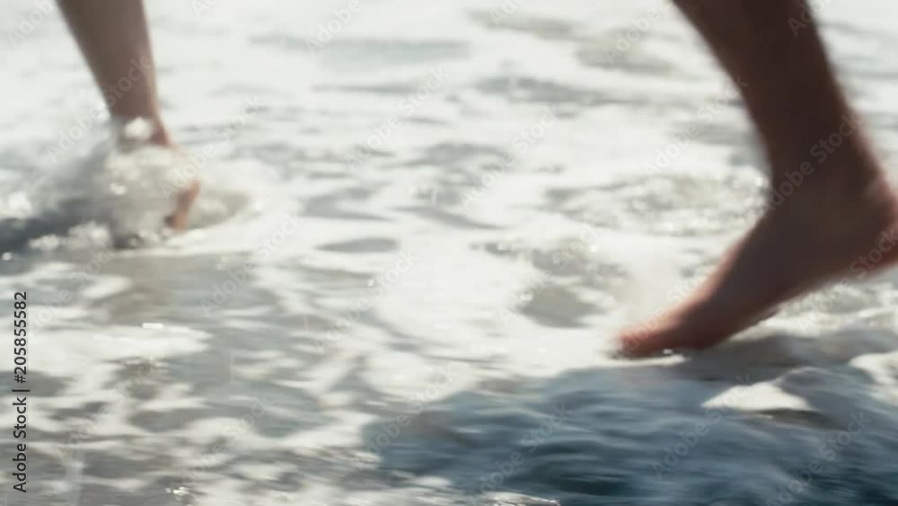 Close up feet walking through waves on beach Close up feet walking through waves on beach