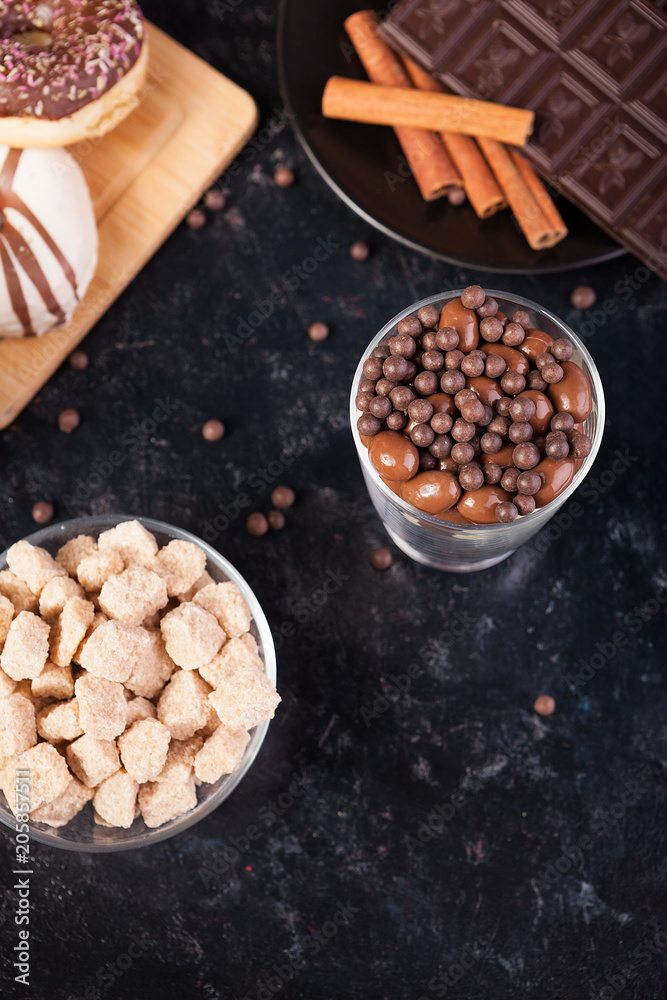 Chocolate tablet next to other candies on dark wooden background