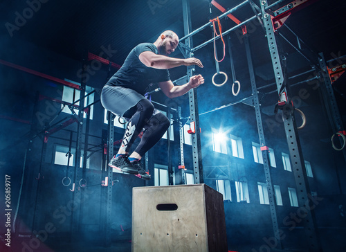 Man jumping during exercises in the fitness gym. CrossFit.