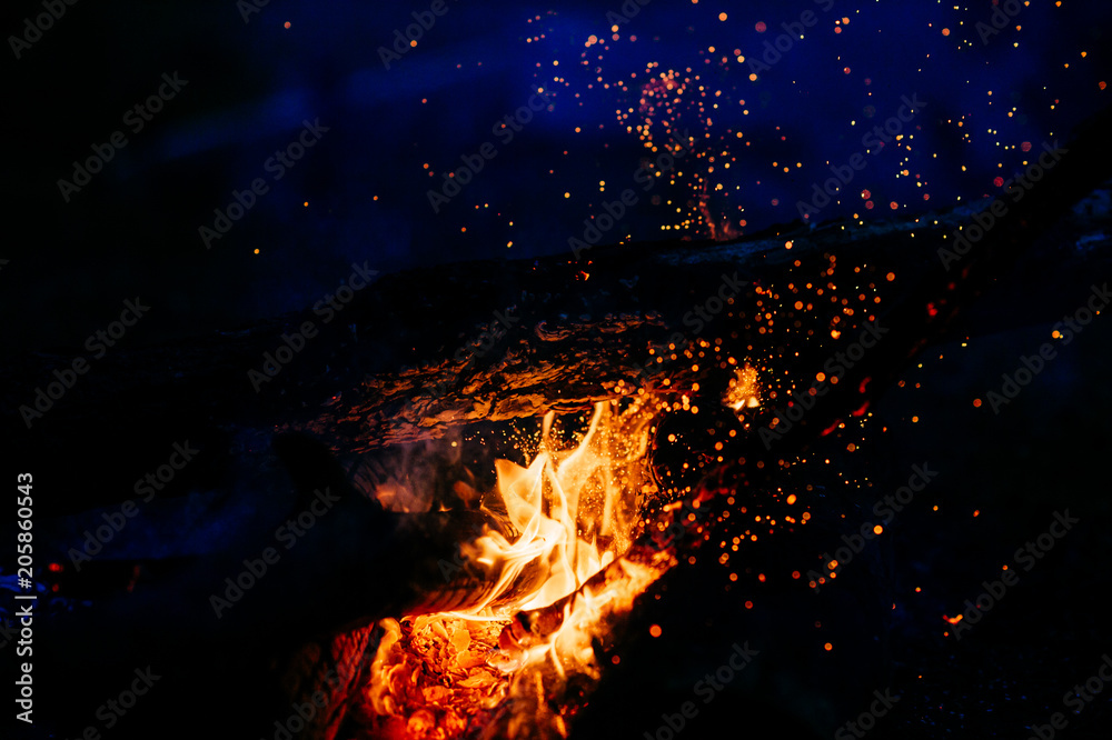 Burning wood at night. Campfire at touristic camp at nature in mountains. Flame amd fire sparks on dark abstract background. Cooking barbecue outdoor. Hellish fire element. Fuel, power and energy. Burning wood at night. Campfire at touristic camp at nature in mountains. Flame amd fire sparks on dark abstract background. Cooking barbecue outdoor. Hellish fire element. Fuel, power and energy.