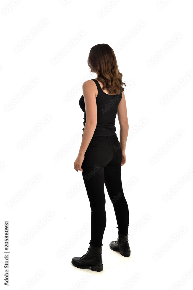 Obraz premium full length portrait of brunette girl wearing black singlet, jeans jeans and boots. standing pose, with back view. isolated on white studio background.