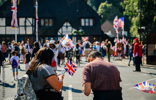Unrecognizable couple with flags using phone on Windsor street for royal wedding marriage celebration of Prince Harry, Duke of Sussex and the Duchess of Sussex Meghan Markle 
