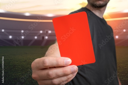 Referee is showing red card as a penalty for a foul in soccer stadium.