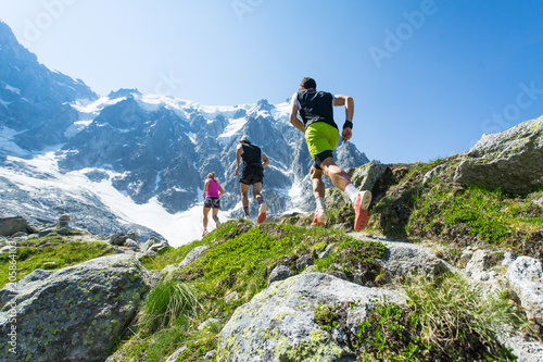 Fototapeta Trail runners running up a steep trail in the Alps in summer