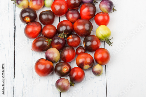 Different tomatoes on the white wooden background