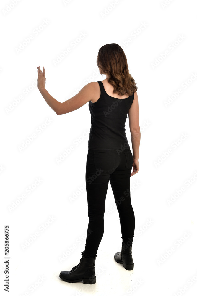 full length portrait of brunette girl wearing black singlet, jeans jeans and boots. standing pose, with back view. isolated on white studio background. full length portrait of brunette girl wearing black singlet, jeans jeans and boots. standing pose, with back view. isolated on white studio background.