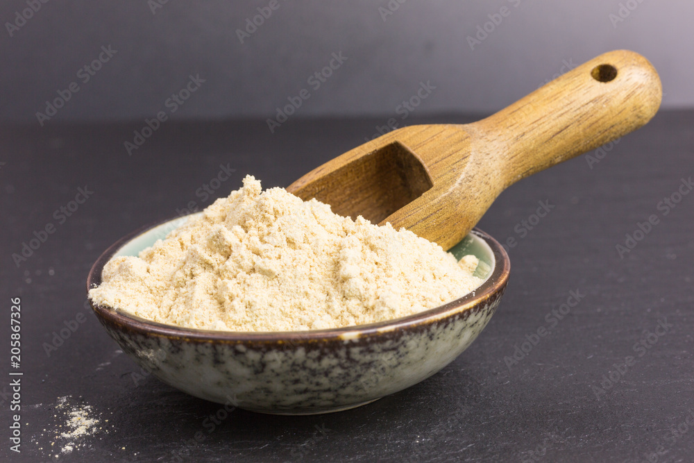 powdered maca root in a bowl with wooden scoop powdered maca root in a bowl with wooden scoop