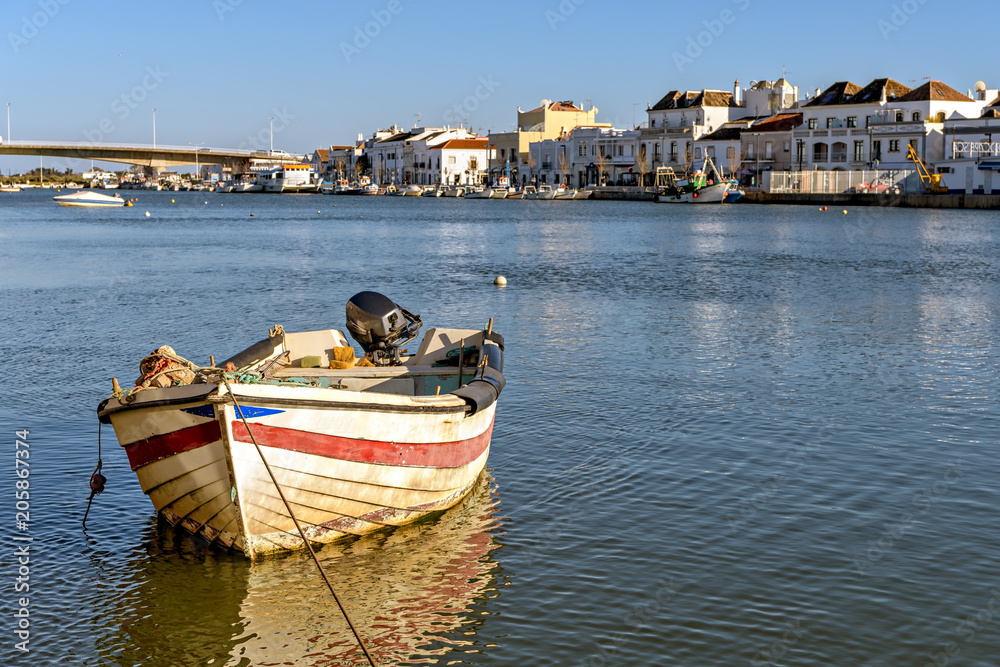 Colorful boat on Gilao river and view of  the city of Tavira, Portugal