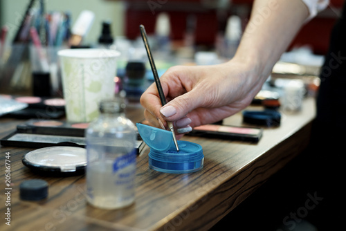 Hands make-up artist with a brush and make-up cosmetics on the table.