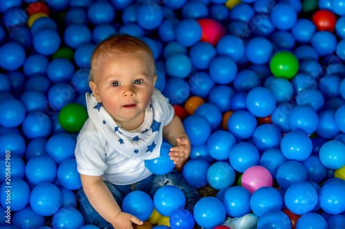 Sweet little toddler child, baby boy, playing in colorful plastic balls