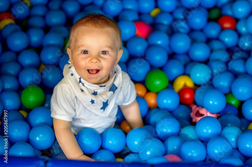 Sweet little toddler child, baby boy, playing in colorful plastic balls