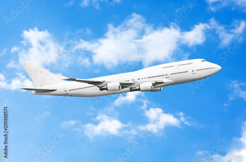 Huge airplane in blue with torn white clouds.