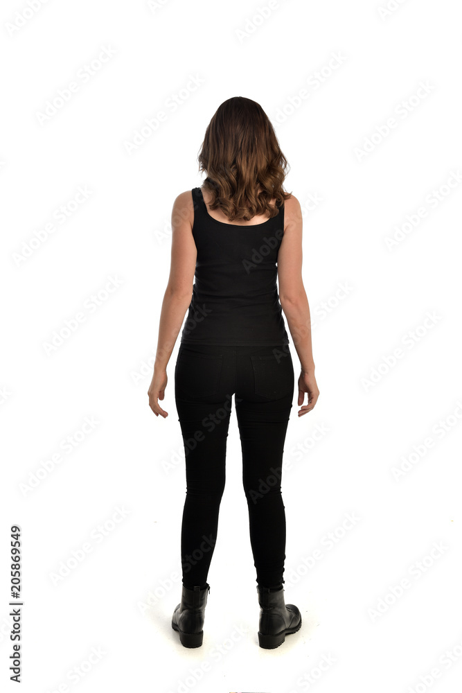 full length portrait of brunette girl wearing black singlet, jeans jeans and boots. standing pose, with back view. isolated on white studio background. full length portrait of brunette girl wearing black singlet, jeans jeans and boots. standing pose, with back view. isolated on white studio background.