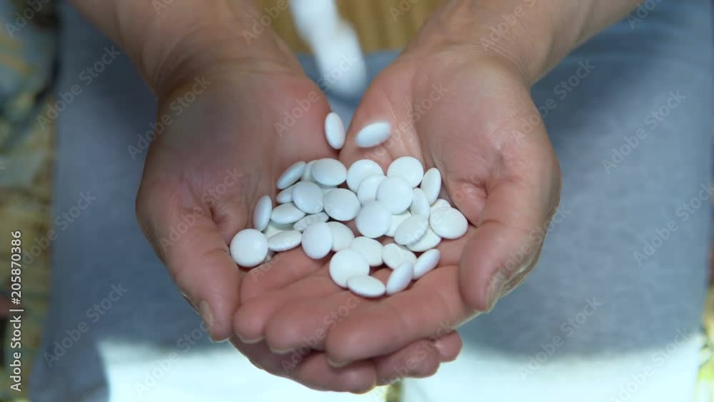 In the hands of an elderly woman pour white pills. In the hands of an elderly woman pour white pills.