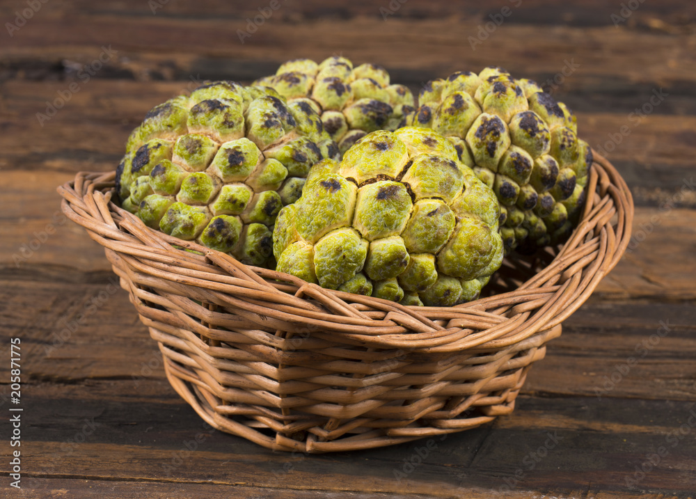 Obraz premium Sweet And Healthy Fruit Custard Apple Also Know as Sitafal, Sweetsop, Annona Squamosa, Sugar Apple, Sitaphal or Anona in Basket on Wooden Table