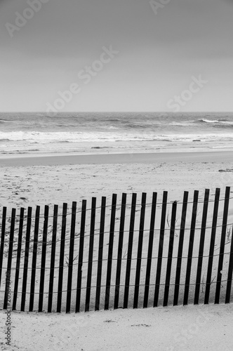 Black and white photo of a beach fence and the ocean