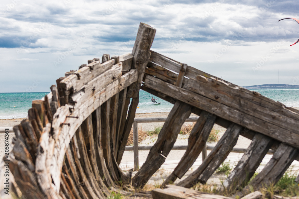 Kitesurf front a old medieval boat's casing on the beach of Spain with beautiful sky landscape and blue sea in the background Kitesurf front a old medieval boat's casing on the beach of Spain with beautiful sky landscape and blue sea in the background