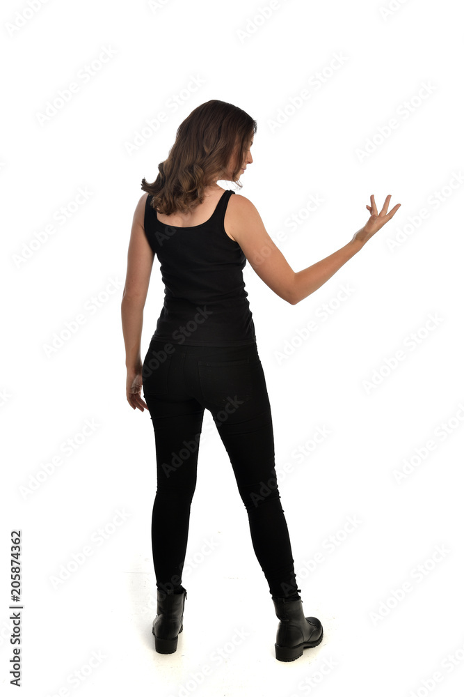 full length portrait of brunette girl wearing black singlet, jeans jeans and boots. standing pose, with back view. isolated on white studio background. full length portrait of brunette girl wearing black singlet, jeans jeans and boots. standing pose, with back view. isolated on white studio background.