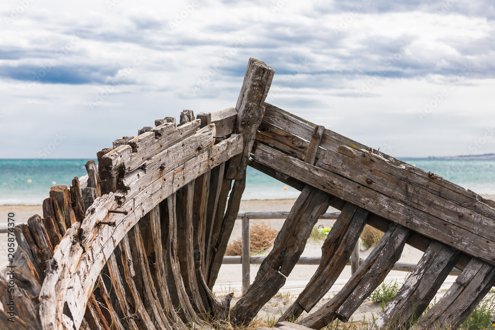 Old medieval boat's casing on the beach of Spain with beautiful sky landscape and blue sea in the background Old medieval boat's casing on the beach of Spain with beautiful sky landscape and blue sea in the background