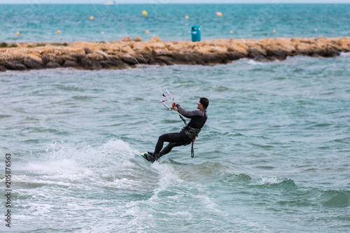 Professional Kitesurfer / Kitesurfing in the Mediterranean sea practicing with his Kiteboarding in the blue sea of the Mediterranean in the middle of winter