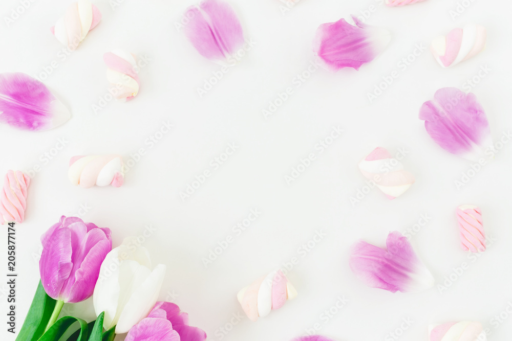 Round frame with pink tulips with petals and marshmallow on white background. Flat lay, Top view.