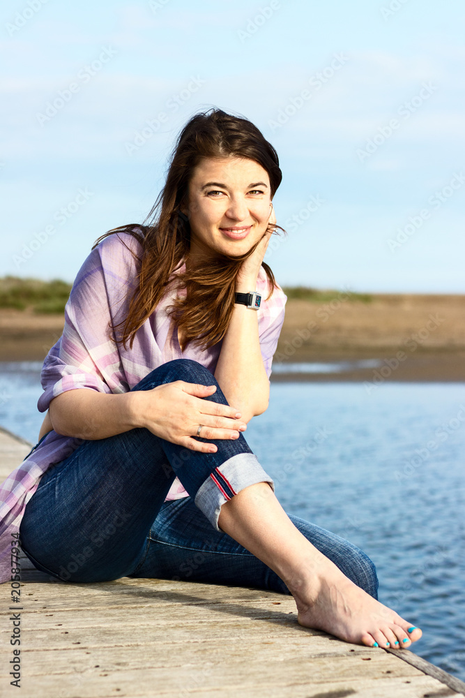 European woman on a wooden bridge looking at camera smiling