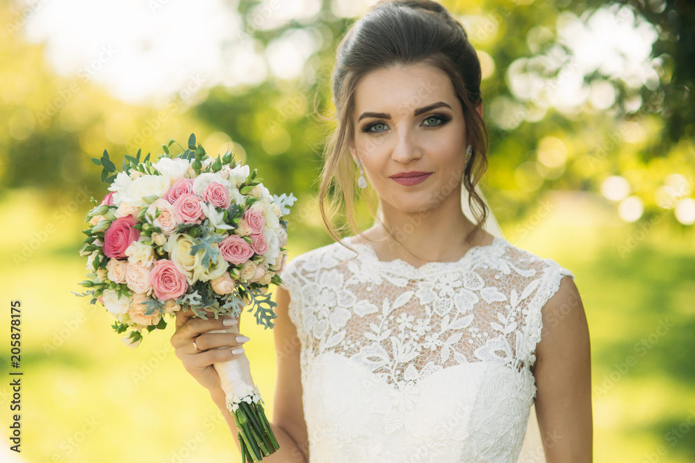 Beautiful bride hold a bouquet in hands. Happy bride smile to the photographet Beautiful bride hold a bouquet in hands. Happy bride smile to the photographet