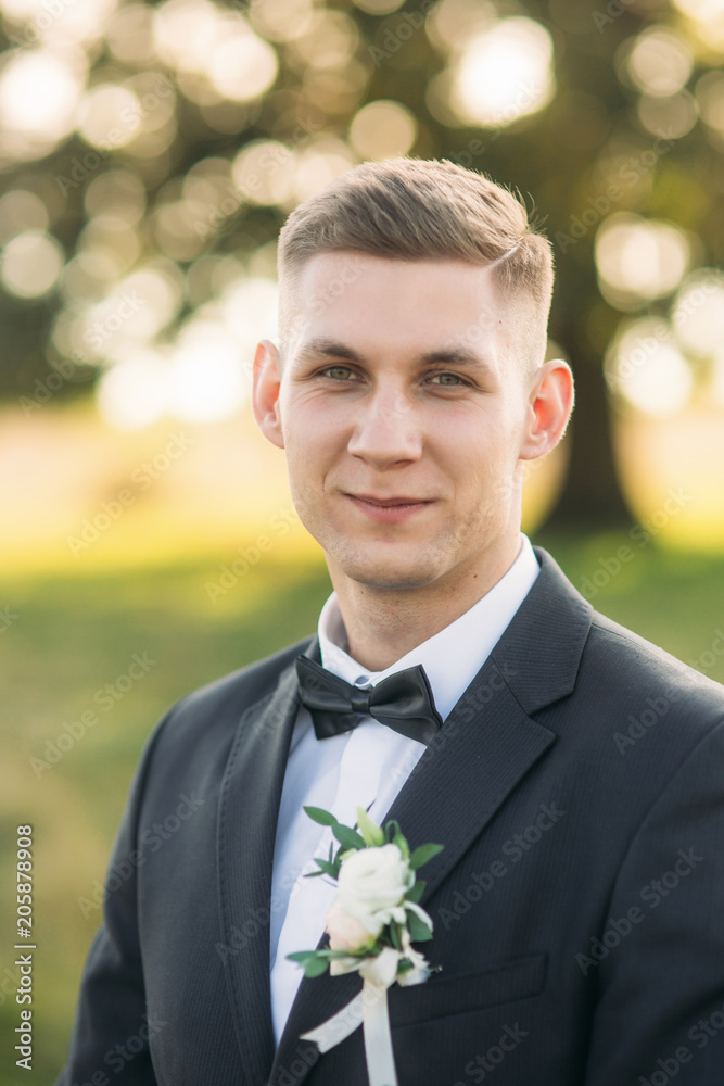 Groom standing in the middle of field in the background of big tree