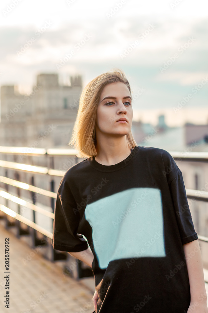 beautiful young blonde girl on the city background during sunset