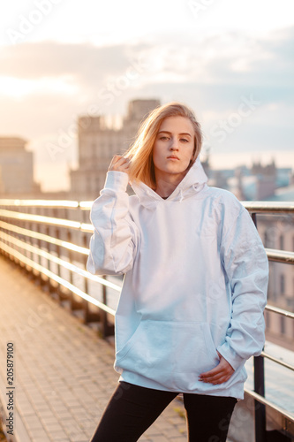 beautiful young blonde girl on the city background during sunset