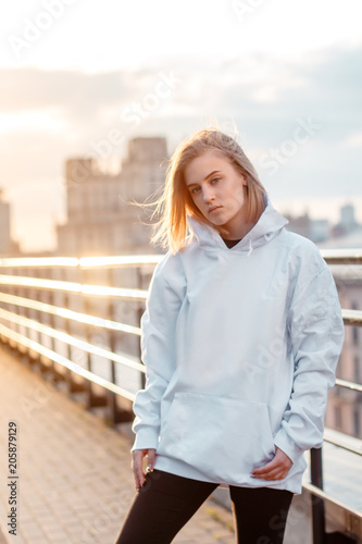 beautiful young blonde girl on the city background during sunset