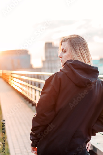 beautiful young blonde girl on the city background during sunset