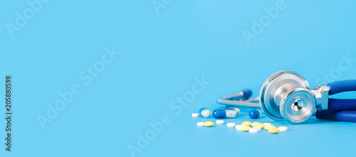 Obraz na plátne Stethoscope and pills on blue background copy space