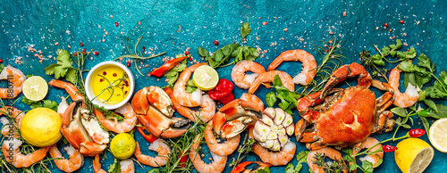 Baner. Fresh raw seafood - shrimps and crabs with herbs and spices on turquoise background. Copy space