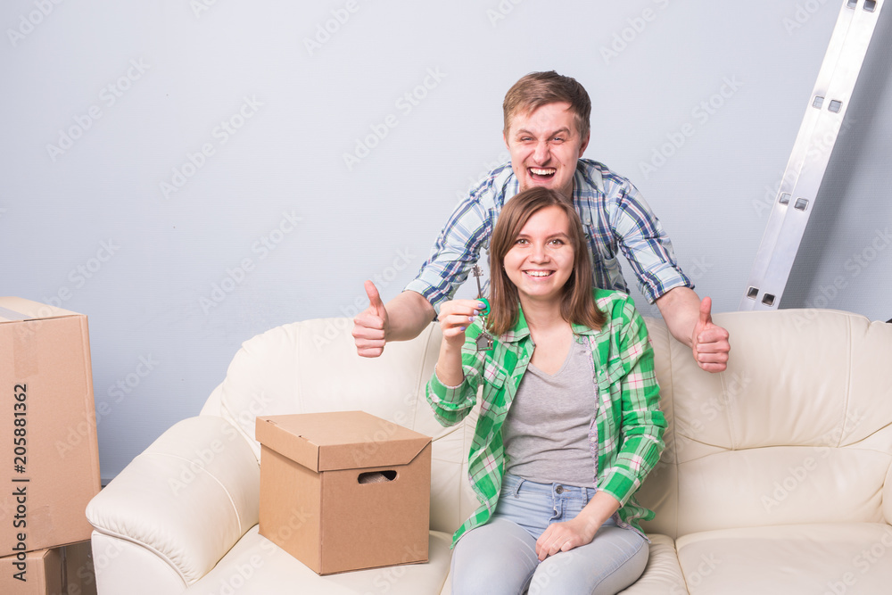 Young married couple with boxes and holding flat keys.