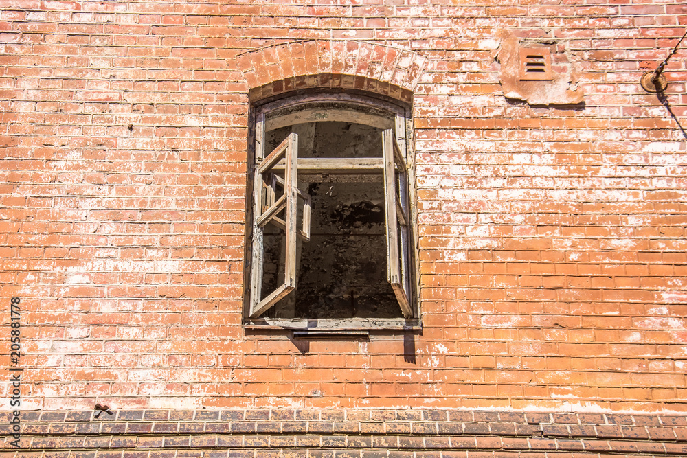 Old red brick wall with destroyed window.