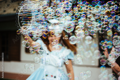 young girl produces many soap bubbles with large circle