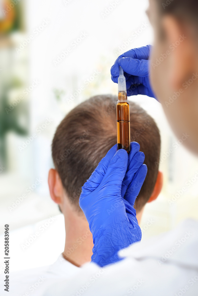 Fototapeta premium Łysieie. Mężczynma u trychologa. Kosmetyki i preparaty lecznicze na porost włosów.