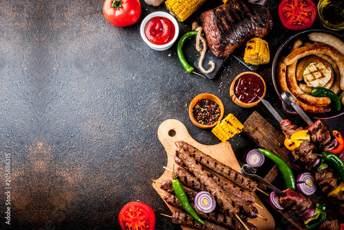 Fototapeta Naklejka Na Ścianę i Meble -  Assortment various barbecue food grill meat, bbq party fest - shish kebab, sausages, grilled meat fillet, fresh vegetables, sauces, spices, dark rusty concrete table, above copy space
