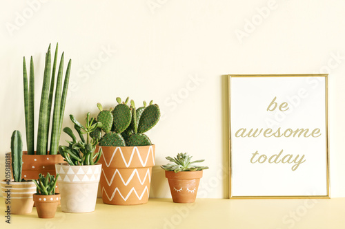 Stylish and modern composition of yellow interior filled a lot of cacti and succulents in different pattern pots with gold mock up frame. 