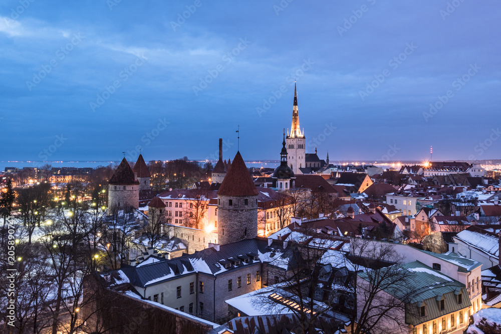 Obraz premium Twilight over the Tallinn old town cityscape with the Saint Olaf church and the medieval fortified wall in Estonia capital city.