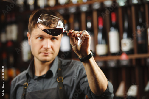 Bokal of red wine on background, male sommelier appreciating drink photo