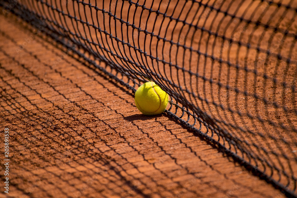 Tennis net with fast tennis ball on clay court