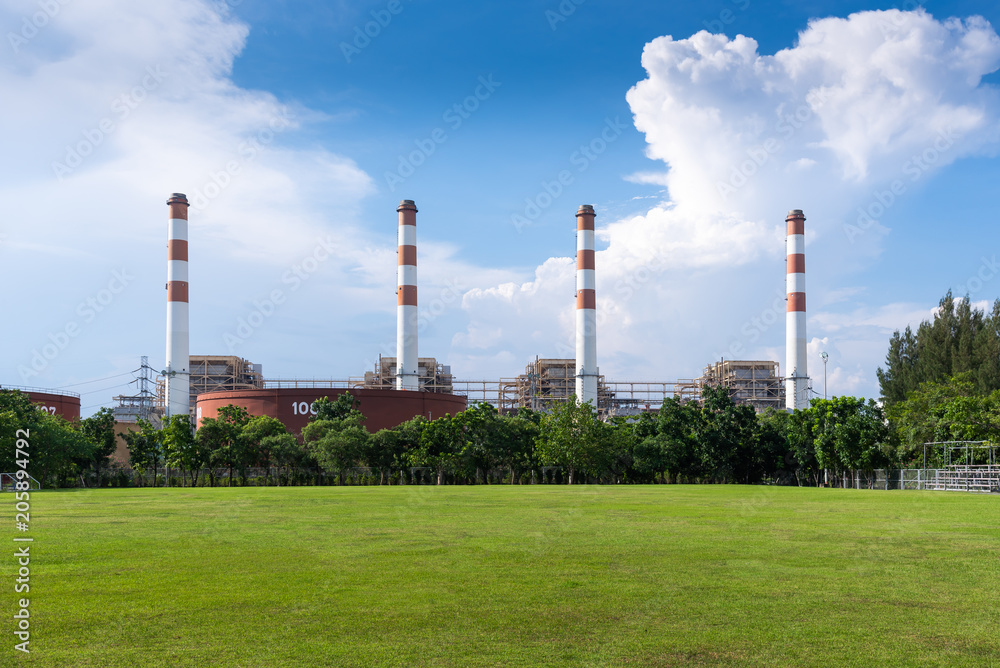 The abstract image of many pipe of power plant and the lawn and cloudy sky is backdrop.  The concept of power plant, engineering, clean energy, construction and electricity.