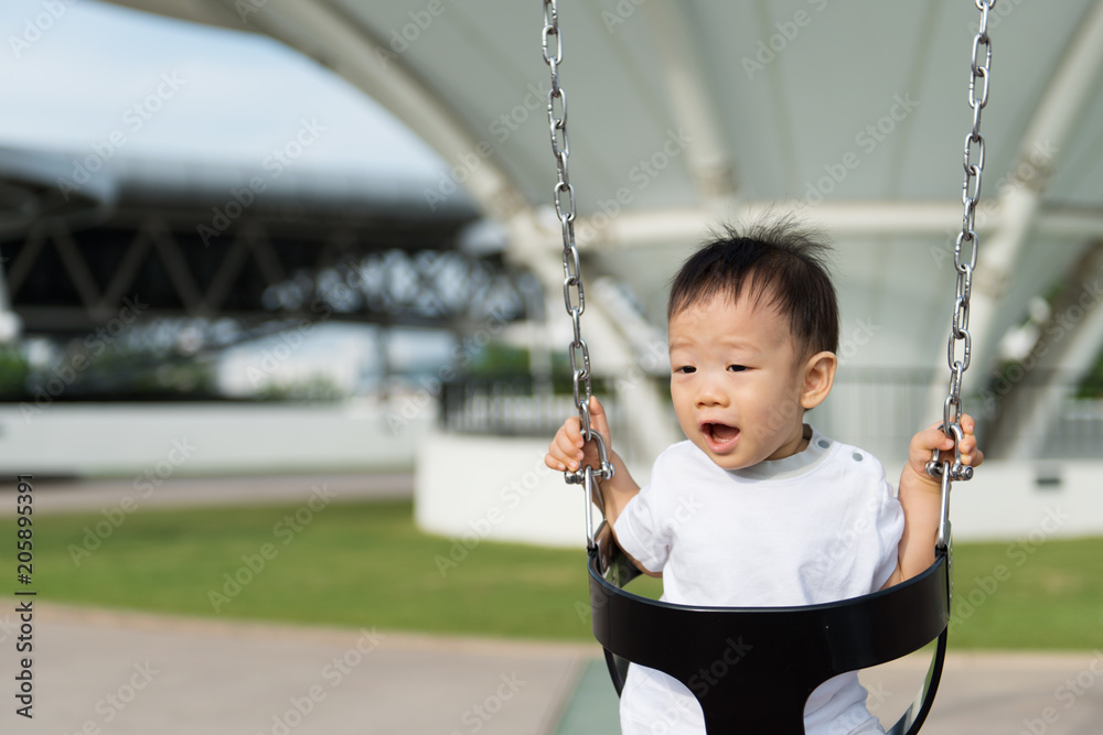 Adorable little Asian baby boy in swing at outdoor playground Adorable little Asian baby boy in swing at outdoor playground