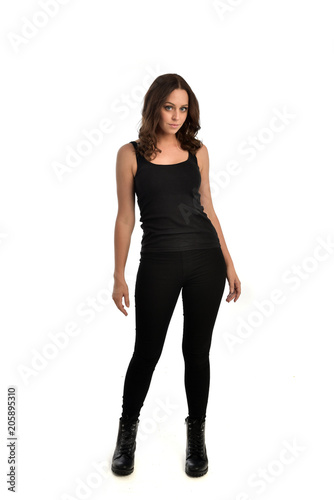 full length portrait of brunette girl wearing black singlet, jeans jeans and boots. standing pose, isolated on white studio background.